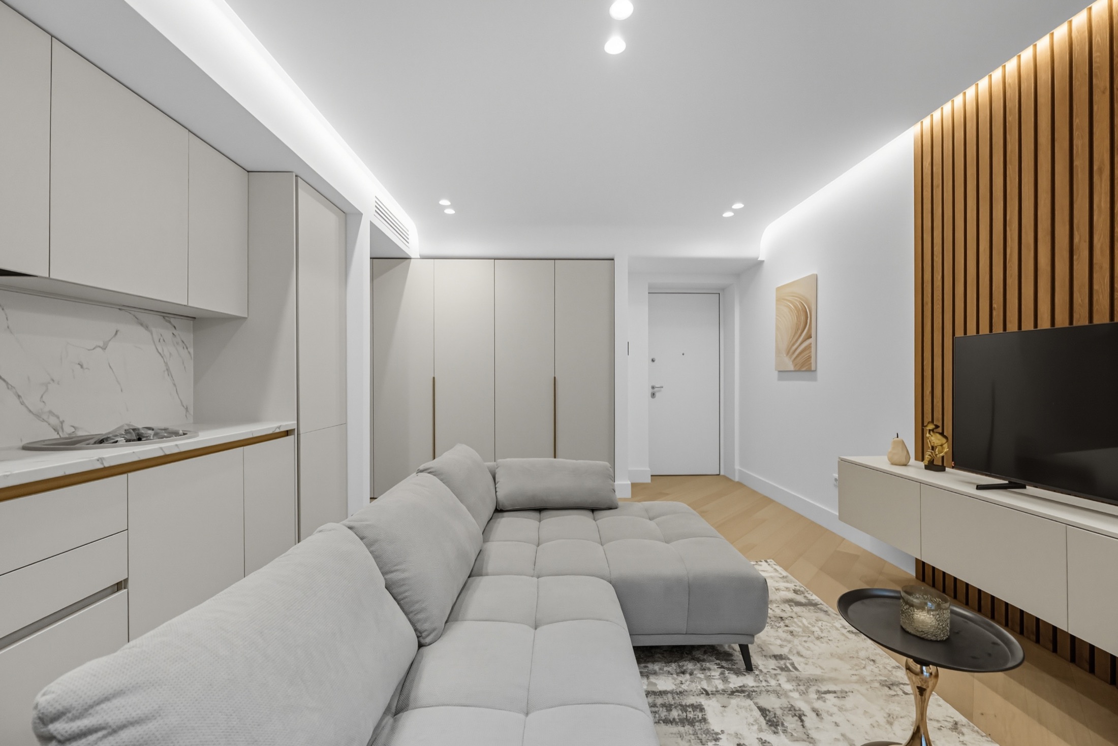 Open-plan living space with white joinery and timber feature wall